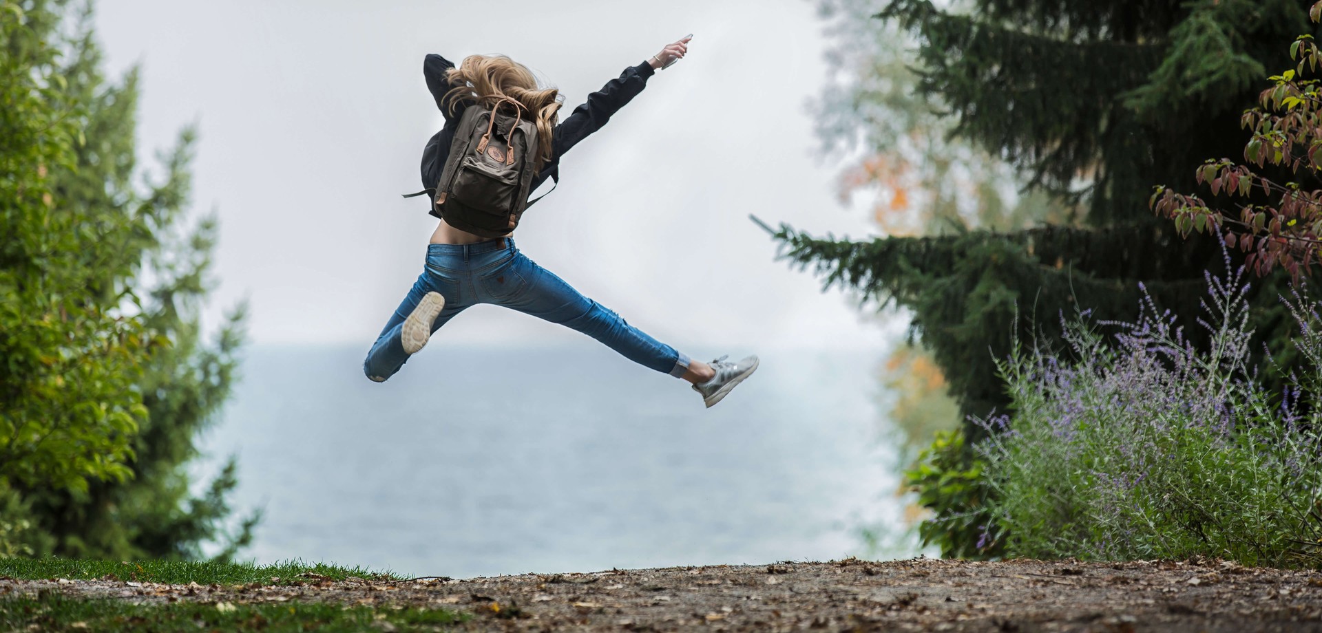 Das Bild zeigt ein Mädchen von hinten, das in der Natur in die Luft springt. ©Pexels / Sebastian Voortman