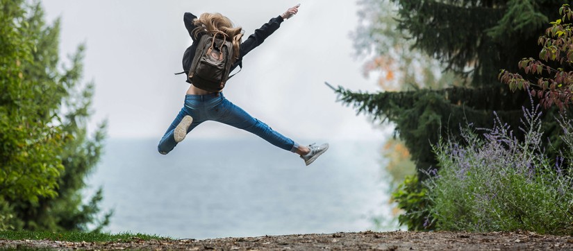 Das Bild zeigt ein Mädchen von hinten, das in der Natur in die Luft springt. ©Pexels / Sebastian Voortman