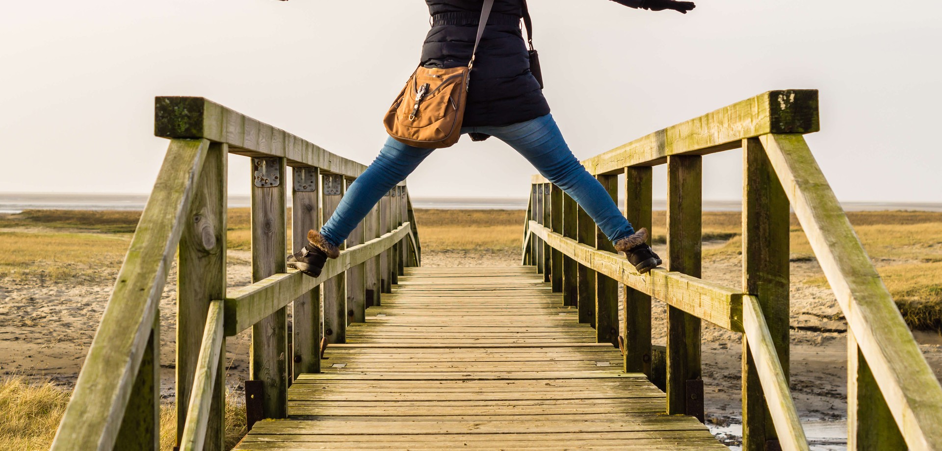 Das Bild zeigt ein Mädchen am Meer, dass auf dem Geländer eines kleinen Holzsteges steht. ©AdobeStock / Animaflora PicsStock
