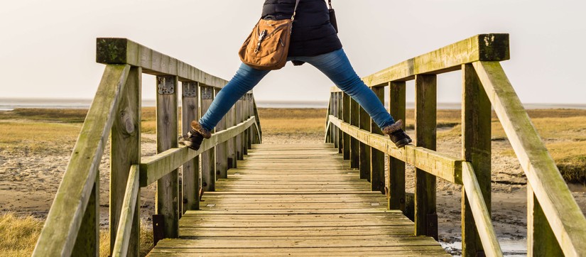 Das Bild zeigt eine Person, die breitbeinig auf dem Geländer eine Brücke steht. © AdobeStock / Animaflora PicsStock